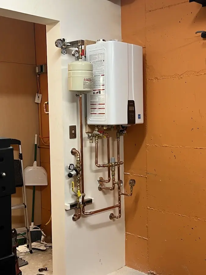 Plumbing technician inspecting water heater connections in Pittsford